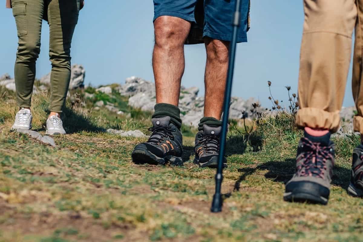 Group of three people practicing trekking outdoors. Selective focus on man in background and their shoes.