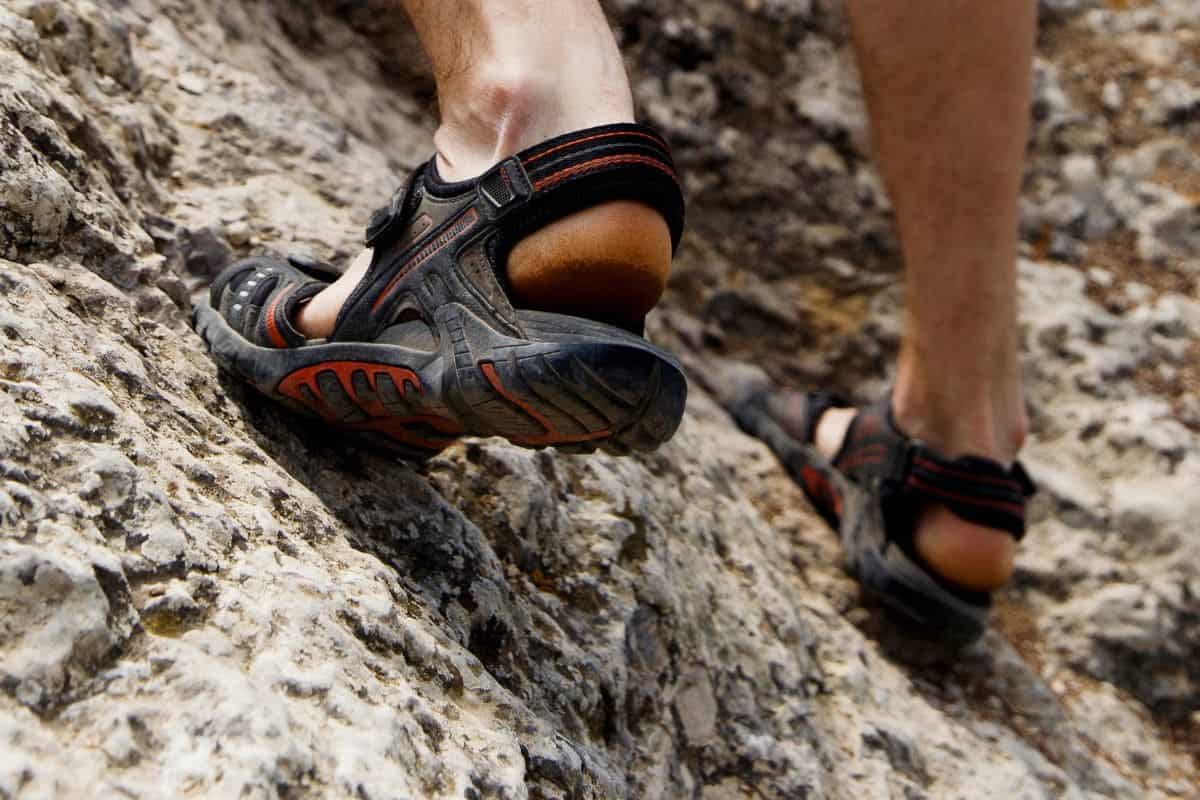 Guy climbs on rock mountains on his hiking sandals.