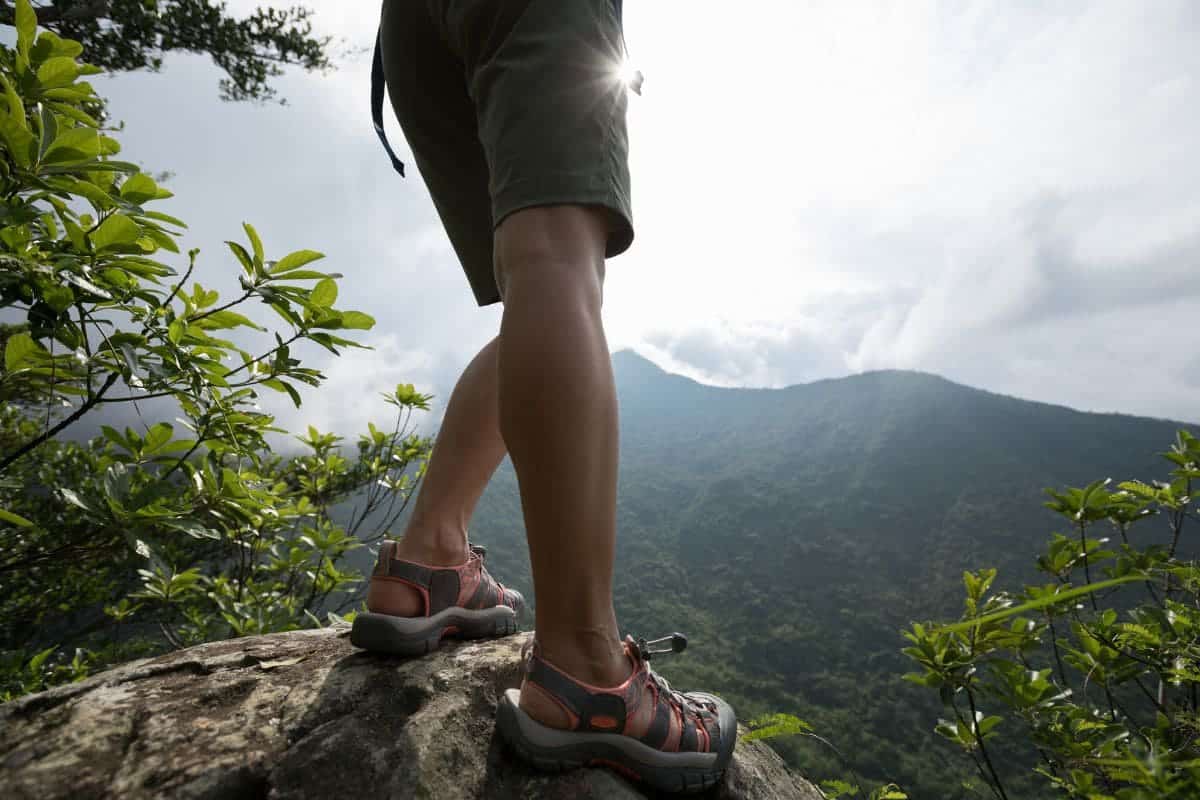 hiker enjoy the view on sunrise mountain top cliff edge on his hiking sandals.