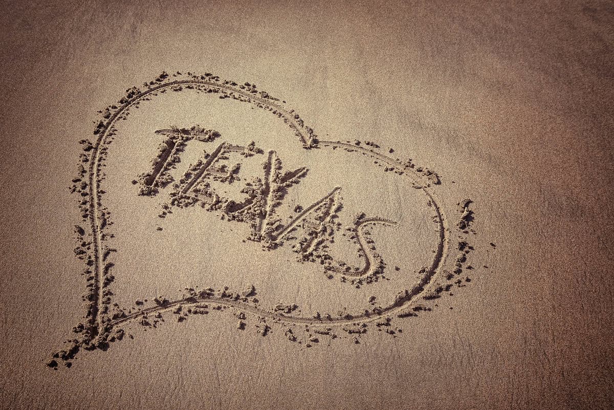 Texas and heart written on beach sand.