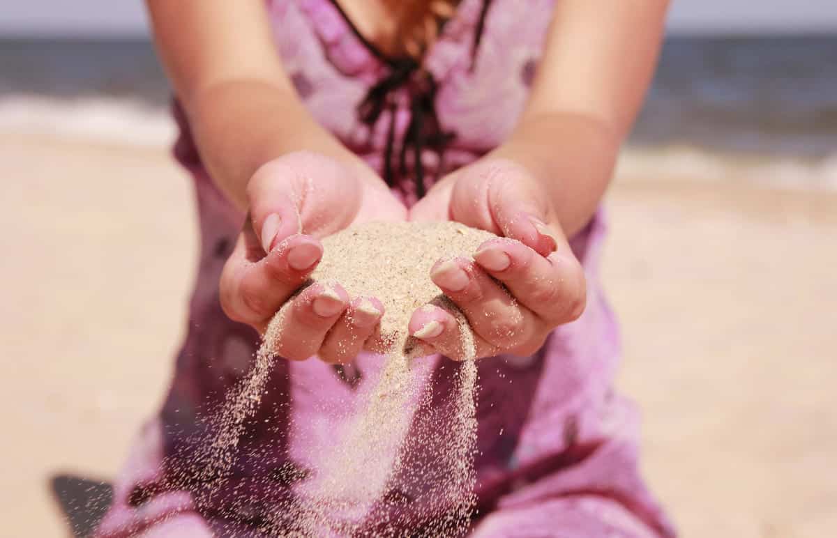 a women pouring sand into their hands.